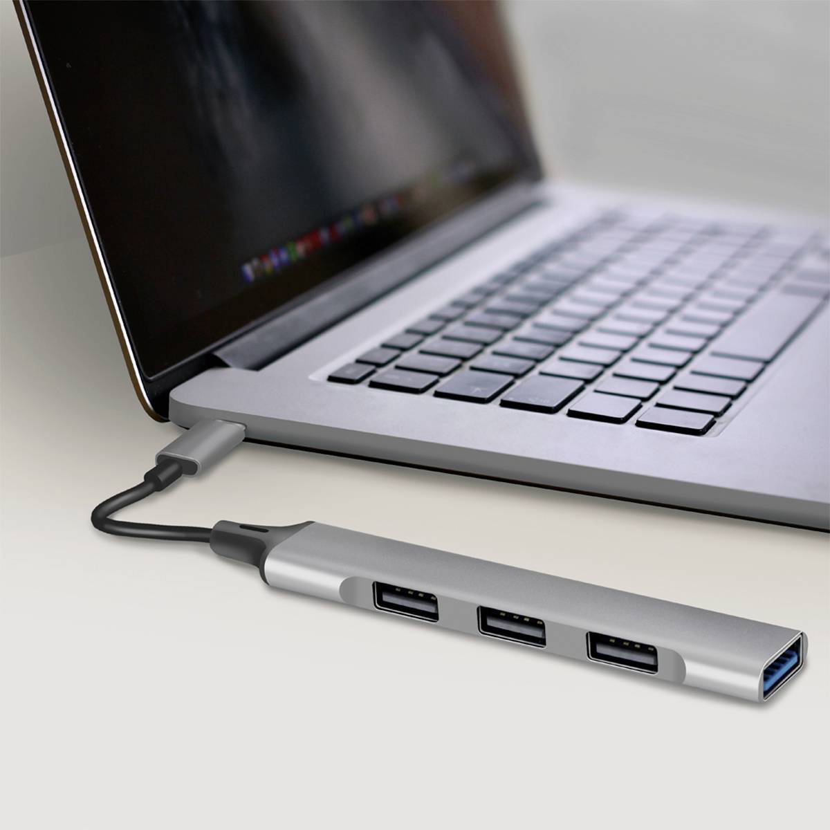 Laptop z dokującą stacją USB-C, połączony za pomocą kabla. Stacja dokująca posiada kilka portów USB.