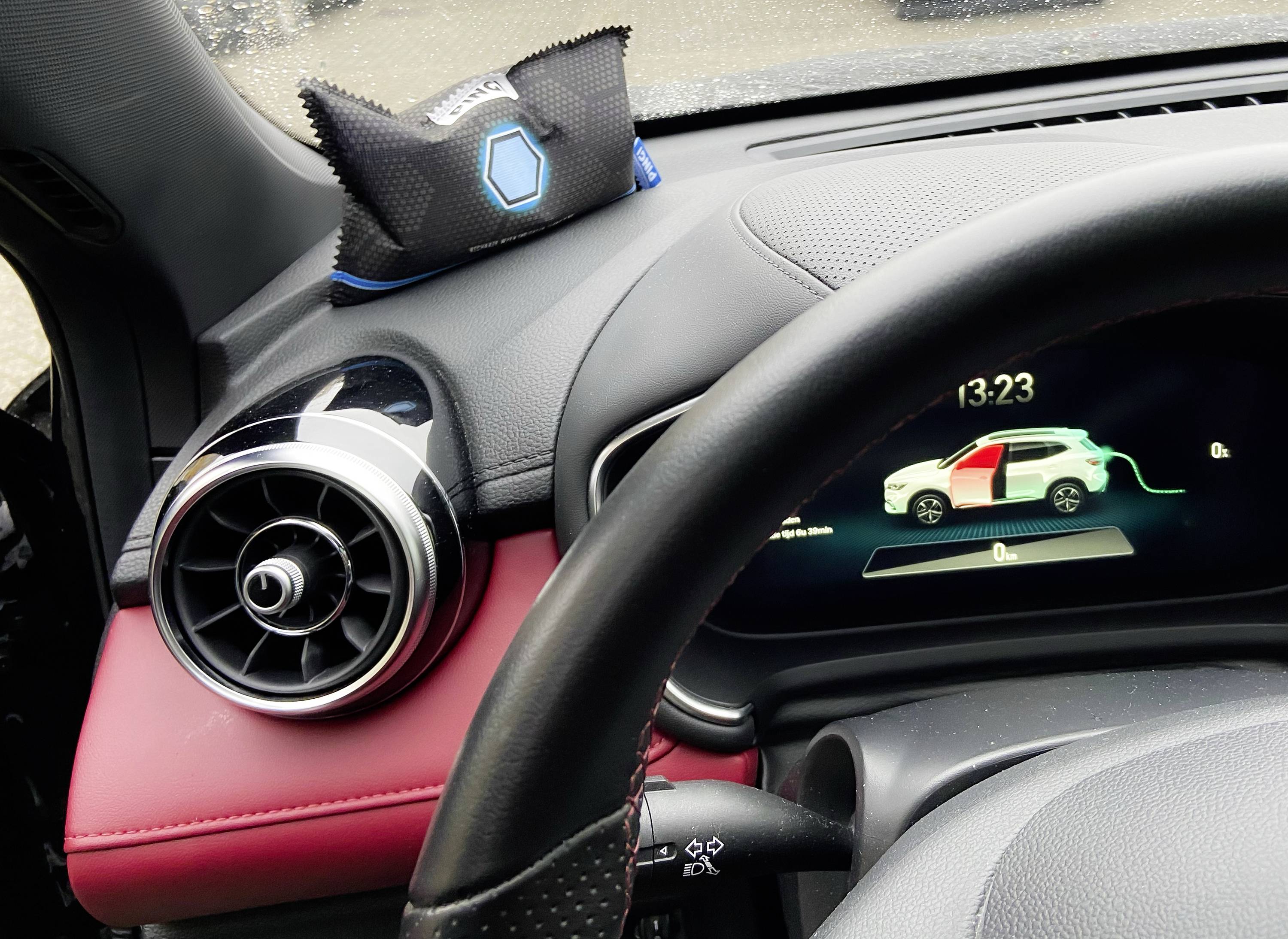 Kierownica samochodu z wyświetlaczem cyfrowym pokazującym stan ładowania pojazdu elektrycznego; godzina 13:23.