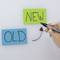 Dwie karteczki samoprzylepne, po lewej stronie zielona z napisem 'OLD', a po prawej stronie niebieska z napisem 'NEW'. Ręka trzyma długopis, który rysuje strzałkę.