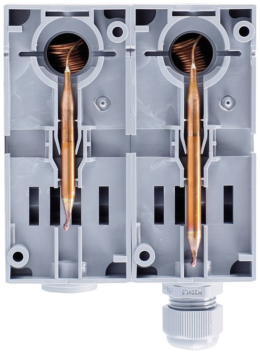 Elektryczny element składowy z dwoma miedzianymi cewkami, umieszczony w szarych obudowach, prawdopodobnie stanowiący część większej instalacji elektrycznej.