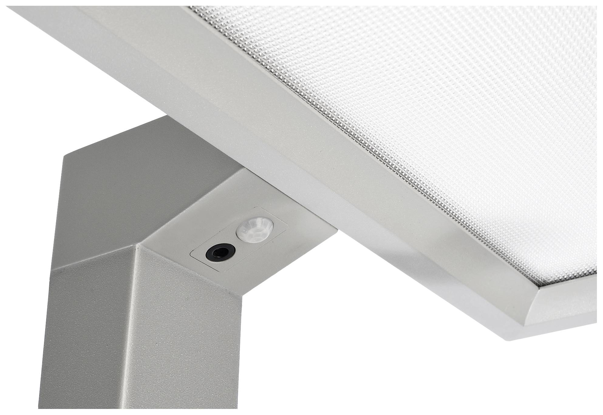 Zbliżenie srebrnej lampy z czujnikiem ruchu na spodniej stronie. Powierzchnia jest ryflowana.