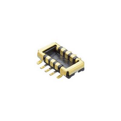 Prostokątny element elektroniczny z sześcioma metalowymi stykami leżący na stole.
