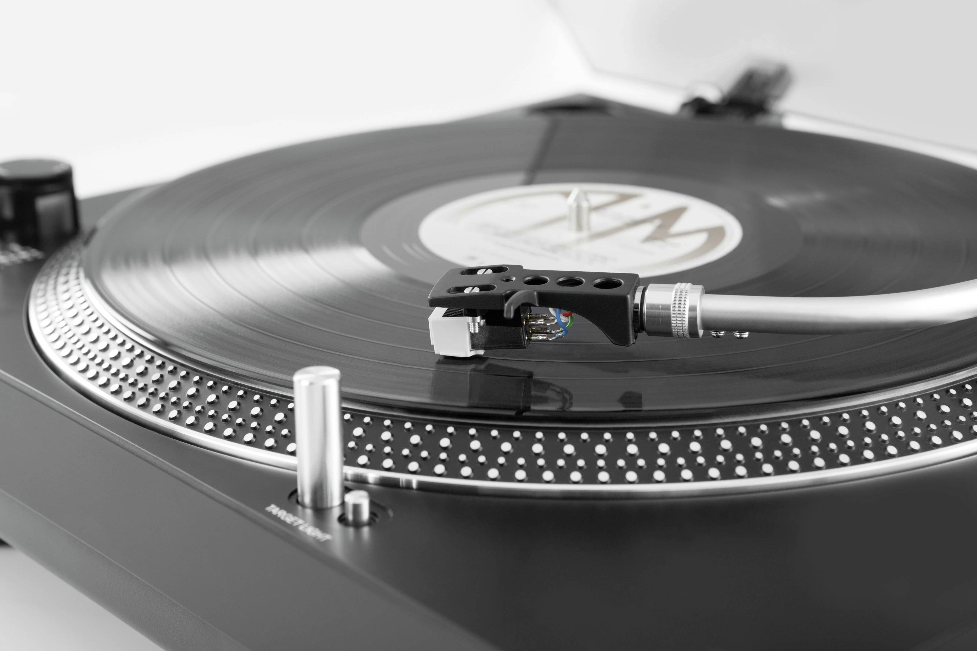 Gramofon z czarną płytą winylową i ramieniem gramofonowym w zbliżeniu.