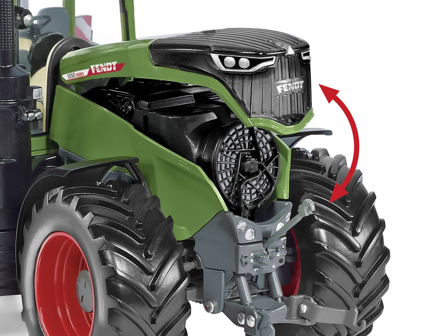 Zabawkowy traktor w kolorze zielonym i czarnym z czerwonymi kołami, oznaczony czerwoną strzałką na szczególe przedniej kraty.