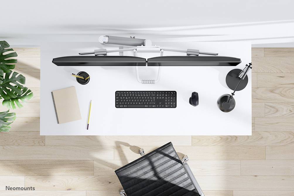 Biurko widziane z góry z klawiaturą, uchwytem monitora, notatnikiem, długopisem, myszą i lampką. Nowoczesne środowisko biurowe.