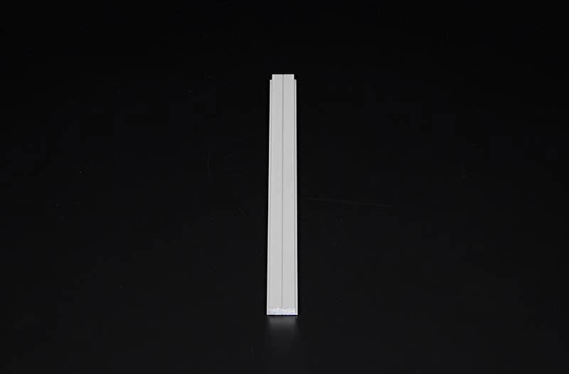 Jedna biała świeca stoi prosto przed czarnym tłem.