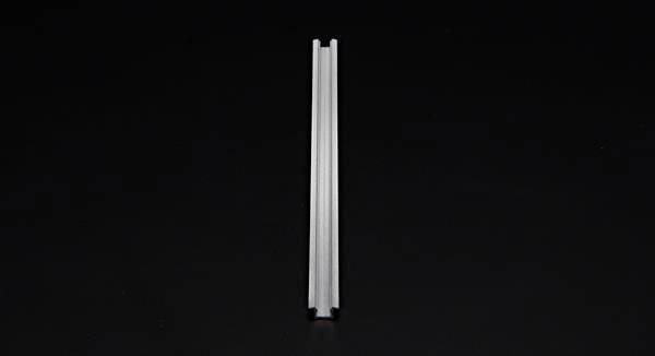 Pojedyncza srebrna szyna leży pionowo w centrum obrazu na czarnym tle.