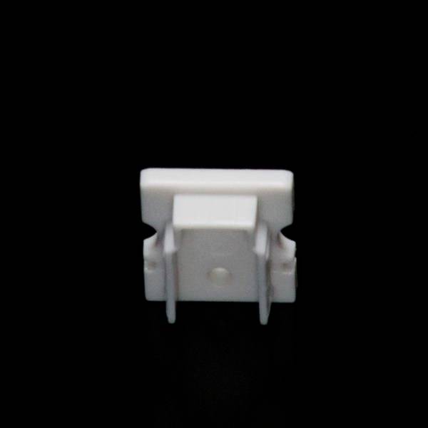 Biały plastikowy klips stoi pionowo na czarnym tle.