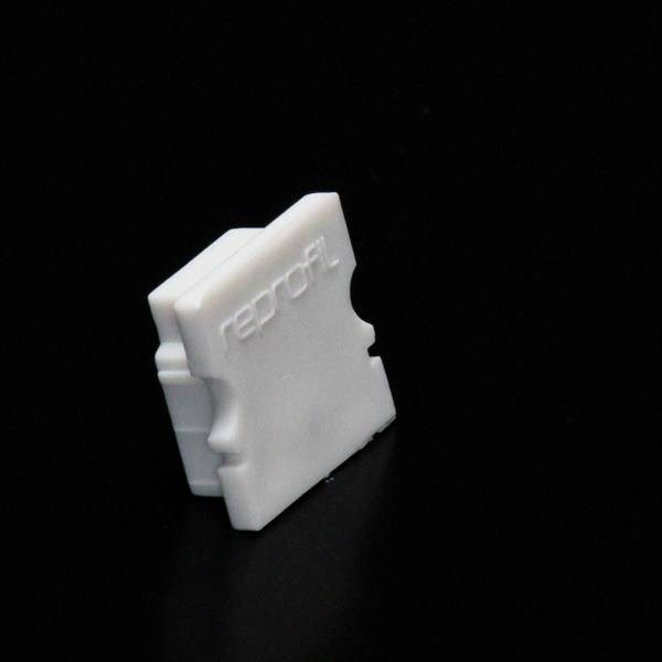 Białe, równomiernie ukształtowane części z tworzywa sztucznego z wytłoczonym napisem 'reprap' widocznym na czarnym tle.