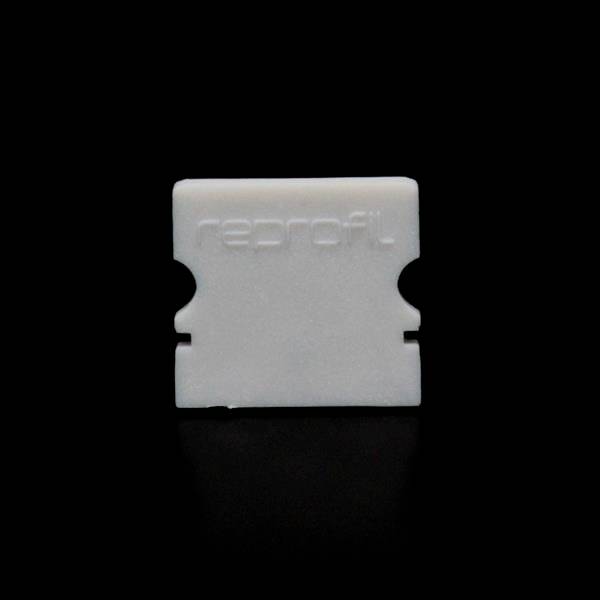 Biała plastikowa osłonka z napisem 'reprofil' na czarnym tle. Wygląda jak ochronna nakładka na ostrza do golenia.