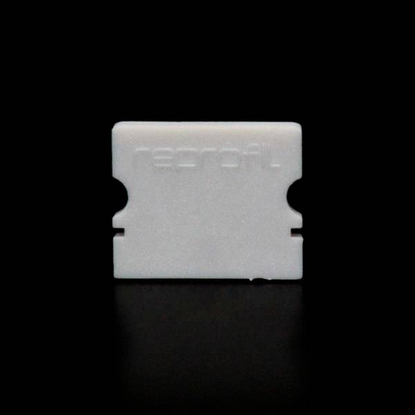 Pojedyncza biała żyletka umieszczona w poziomie na czarnym tle.