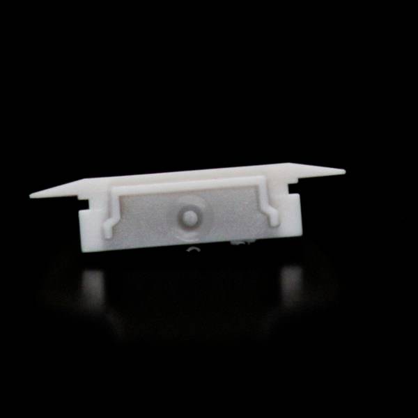 Biały, prostokątny element z tworzywa sztucznego z hakiem na czarnym tle. Wygląda jak część montażowa lub łącznik.
