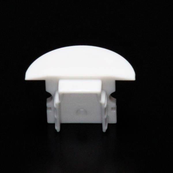 Biała plastikowa nakładka na czarnym tle. Ma zaokrągloną górną powierzchnię i prawdopodobnie służy jako osłona.