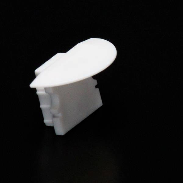 Biała, zaokrąglona plastikowa osłona narożna na czarnym tle.