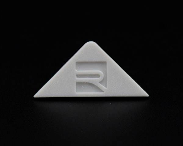 Szary, trójkątny obiekt z wycentrowanym stylizowanym znakiem 'R' na czarnym tle.