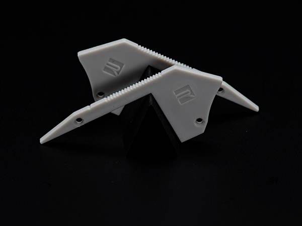 Trzy białe, postrzępione obiekty plastikowe ułożone w kształcie gwiazdy na czarnym tle.