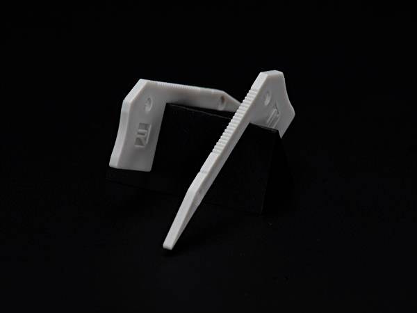 Dwa białe elementy plastikowe na czarnym tle, każdy oparty na czarnym trójkącie.