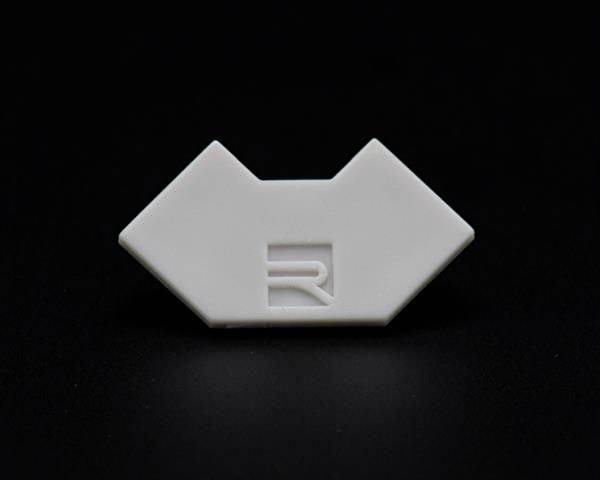 Biała, geometryczna forma z wygrawerowanym logo pośrodku, na czarnym tle.