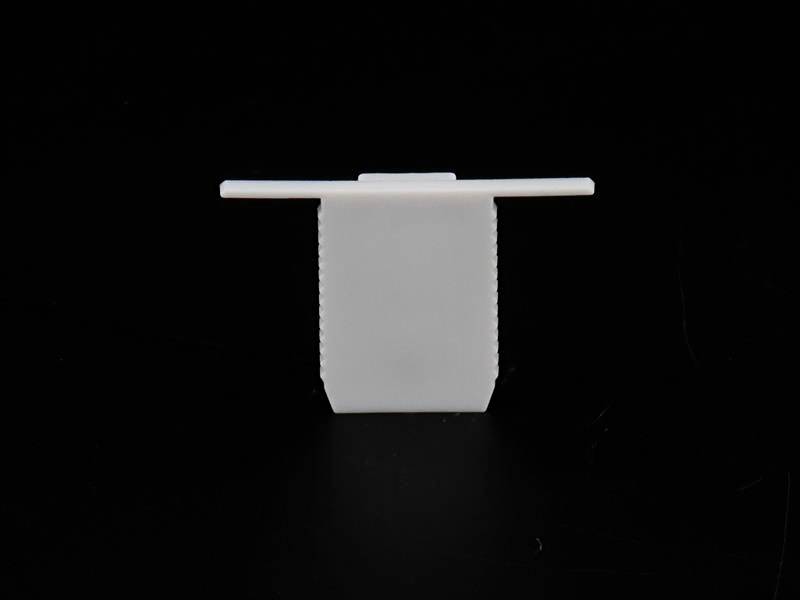 Biała, prostokątna plastikowa opaska mocująca z płaską główką na czarnym tle. Często używana do organizacji przewodów.