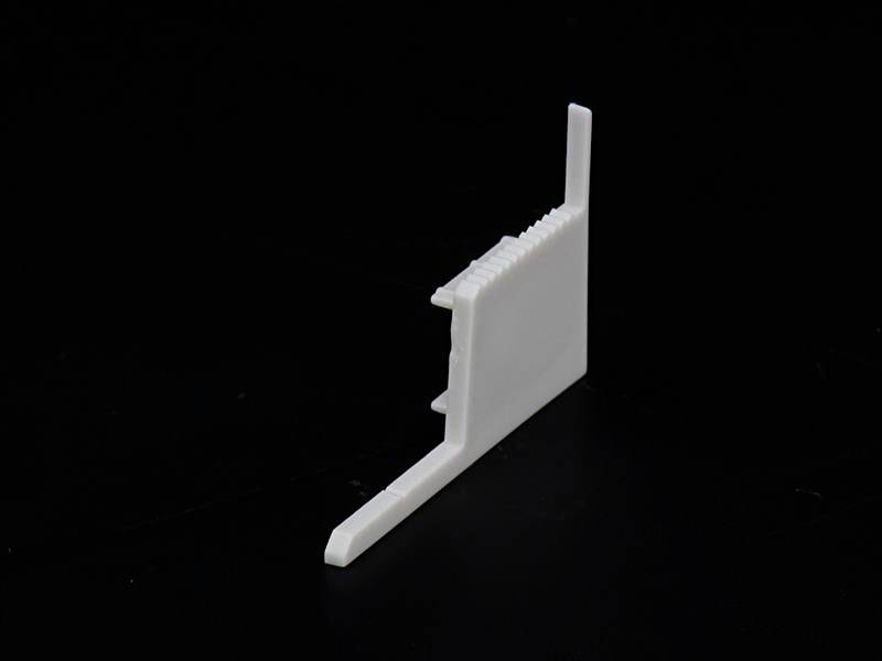 Biały, klinowaty przedmiot z tworzywa sztucznego na czarnym tle.