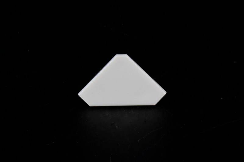 Biała, trójkątna płytka na ciemnym tle.