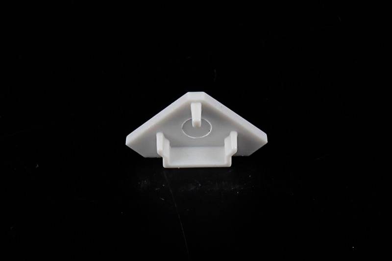 Biały, trójkątny element z tworzywa sztucznego z podniesieniem pośrodku, na czarnym tle.