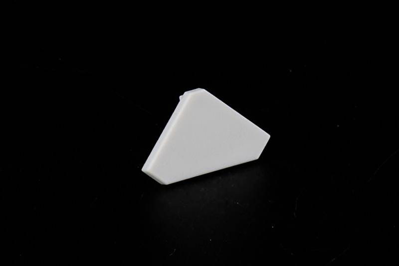 Biały, trójkątny przedmiot leży na czarnym tle.