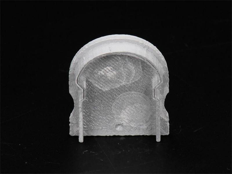 Szary element budowlany z tworzywa sztucznego o łukowato wygiętej górnej powierzchni i dwóch wystającymi stopkami na czarnym tle.