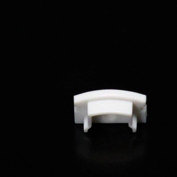 Mały, biały obiekt plastikowy zamocowany na ciemnym tle. Ma zakrzywiony kształt i wydaje się być częścią urządzenia mechanicznego.