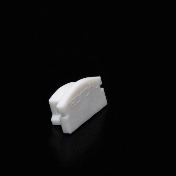 Mały, biały plastikowy przedmiot o prostokątnym kształcie z zaokrąglonymi krawędziami, umieszczony na czarnym tle, nosi napis 'EROI'.