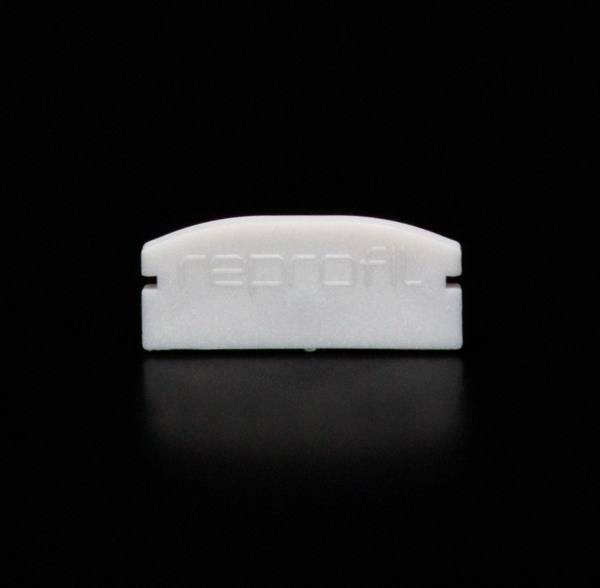 Mały, biały obiekt z tworzywa sztucznego z grawerowanym napisem 'reprofil' leży na czarnym tle.