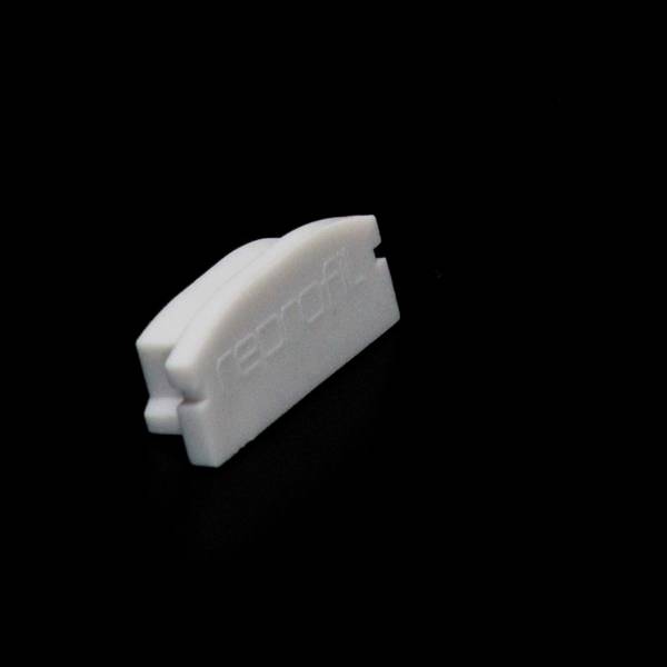 Mały, biały, półkolisty obiekt na czarnym tle, prawdopodobnie z tworzywa sztucznego. Nosi napis 'record'.