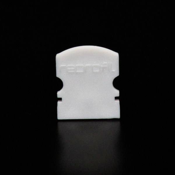 Biała plastikowa tarcza na czarnym tle. Ma zaokrąglony górny brzeg i dwa boczne wcięcia.