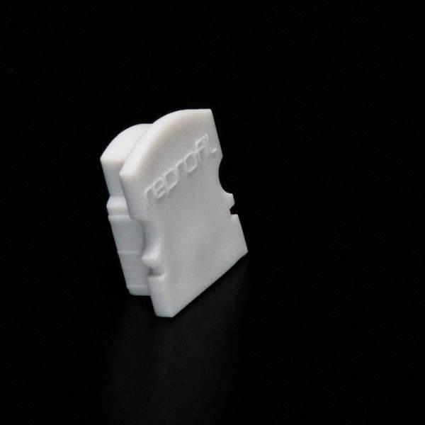 Biały plastikowy klips na czarnym tle z napisem 'profil'.