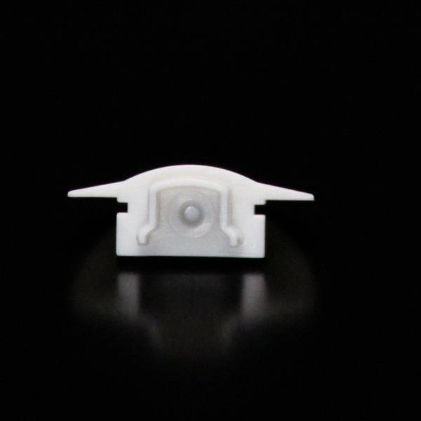 Biała plastikowa część na czarnym tle, która wygląda jak mały, abstrakcyjny samolot.