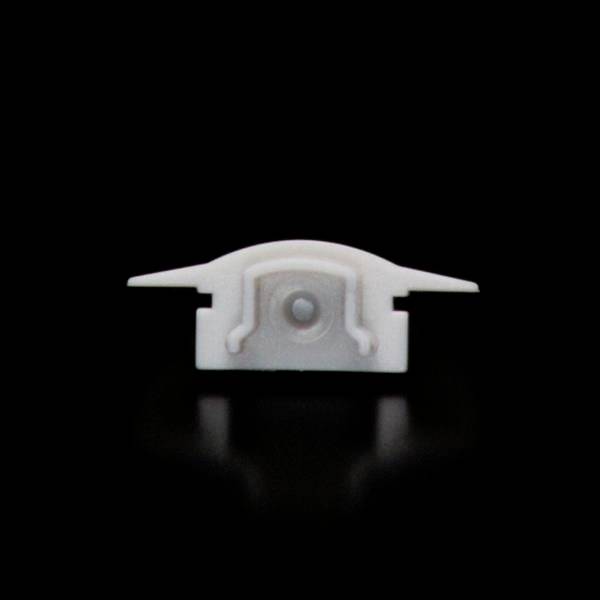 Mały biały przedmiot z dwoma bocznymi rozszerzeniami i widocznym centralnym wypukłością, umieszczony na czarnym tle.