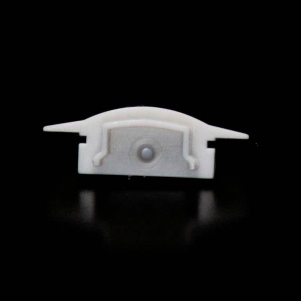 Mała, biała, prostokątna część plastikowa z dwoma skrzydełkami po bokach i centralnym punktem, na czarnym tle.