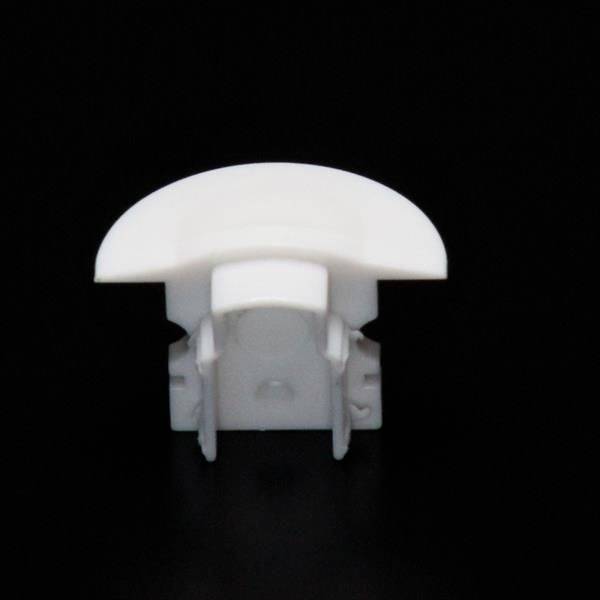 Biała, zaokrąglona plastikowa zatyczka na czarnym tle, prawdopodobnie element mebla lub obudowy.