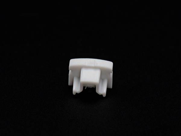 Mała, biała część plastikowa na czarnym tle.