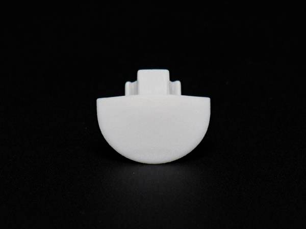 Pojedynczy biały guzik z tworzywa sztucznego na czarnym tle.