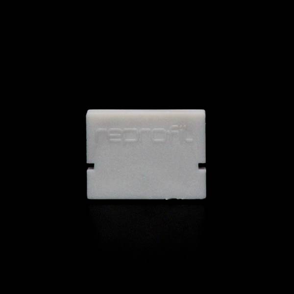 Prostokątny, biały obiekt z wytłoczonym napisem 'reprofit' na czarnym tle.