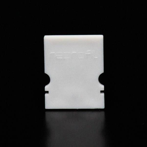 Białe, prostokątne elementy plastikowe z wytłoczonym napisem 'reprofit' na czarnym tle.