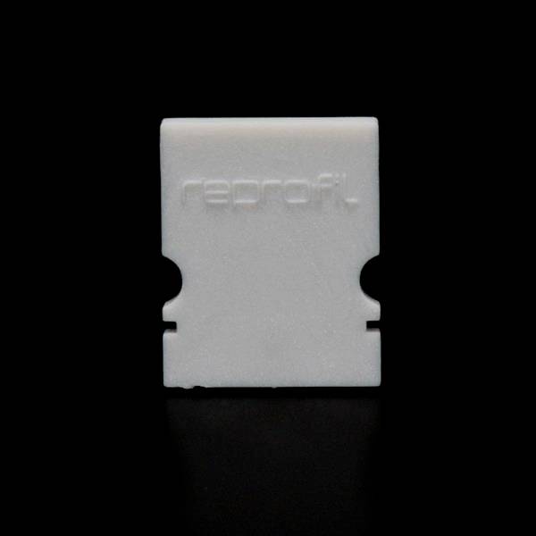 Białą część z tworzywa sztucznego na czarnym tle, na której wygrawerowane jest słowo 'reprofit'. Prostokątny kształt z dwoma symetrycznymi wycięciami po bokach.