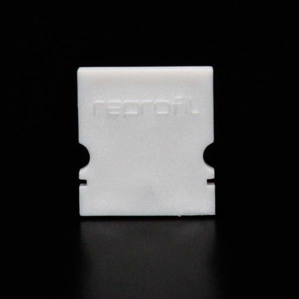 Biała, prostokątna plastikowa osłona na czarnym tle. Z przodu widoczne wypukłe logo 'reprofil'.