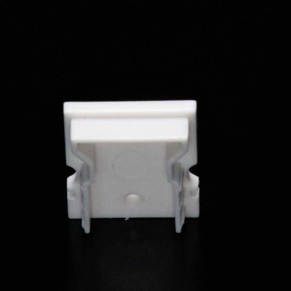 Pojedynczy biały plastikowy klips na czarnym tle, prawdopodobnie używany jako uchwyt do kabli lub do podobnych celów.