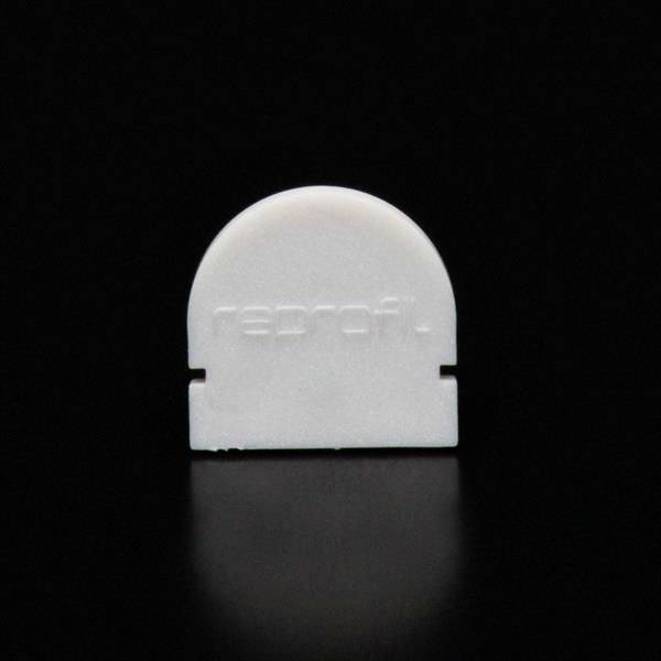 Biała forma z tworzywa sztucznego z napisem 'reprofi.' stoi przed czarnym tłem.