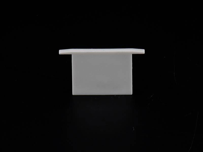 Biały, prostokątny obiekt stoi pionowo na czarnej powierzchni. Tło jest całkowicie czarne.