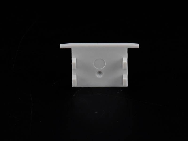Biała plastikowa mocowanie o prostokątnym kształcie, z dwoma zaciskami bocznymi i otworem pośrodku, na czarnym tle.