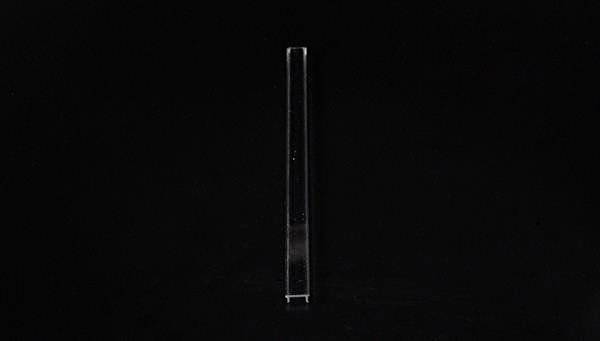 Pojedynczy, długi, przezroczysty pręt stoi pionowo na czarnym tle.