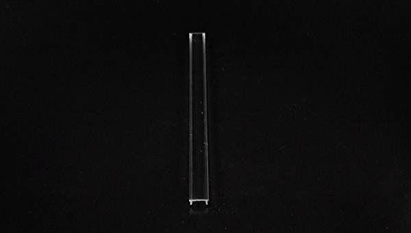 Pojedyncza, przezroczysta rurka plastikowa leży na czarnym tle.